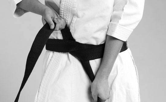 femme qui noue sa ceinture noire sur un kimono