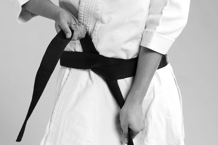femme qui noue sa ceinture noire sur un kimono